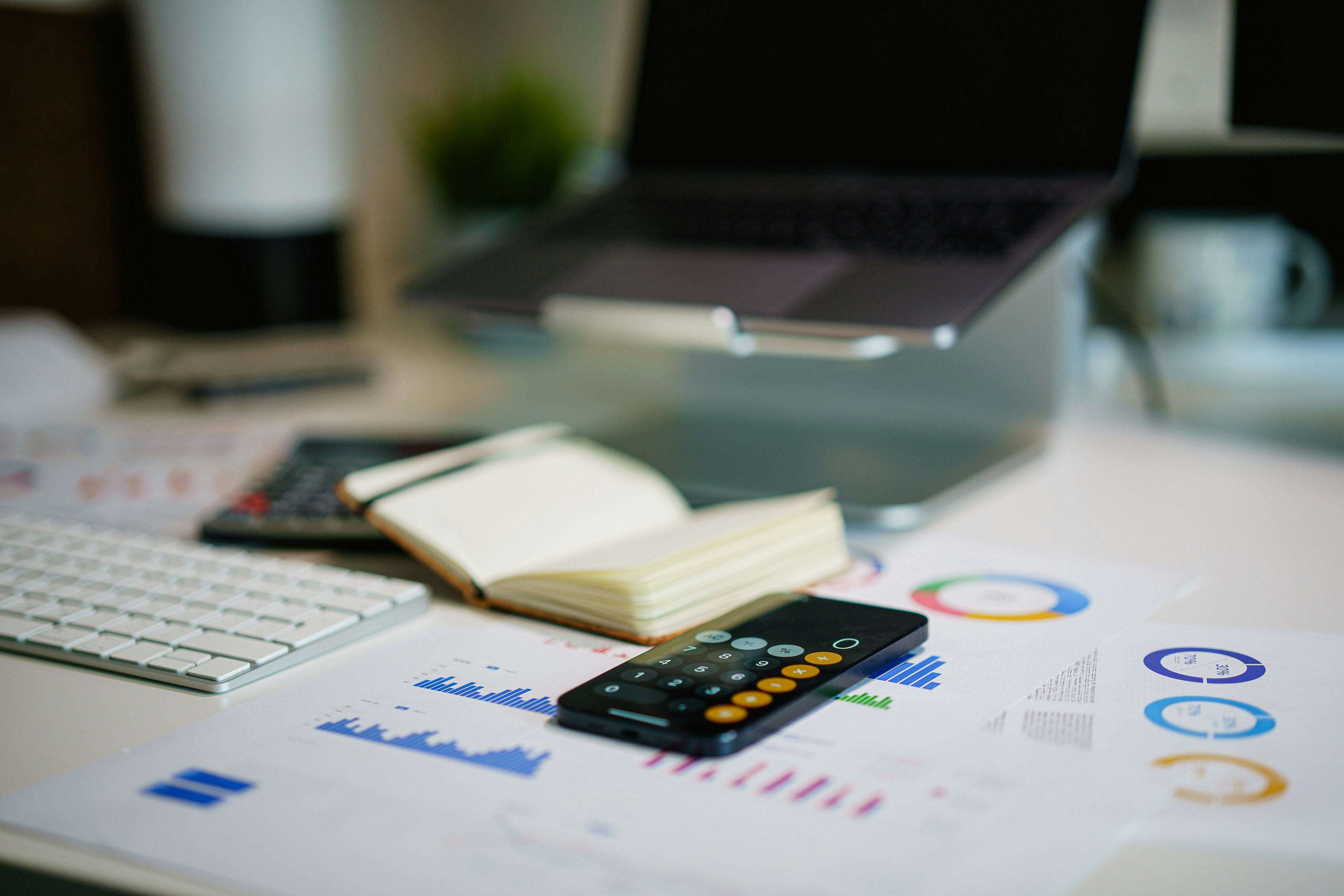 Escritorio de trabajo con portátil, bloc de notas y móvil con calculadora